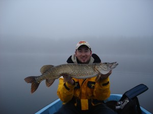 Island house guest with pike caught in lake in front of house